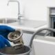 Hands cleaning a clogged dishwasher filter to fix an appliance not draining water