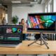 A portable monitor for color grading connected to a laptop showing a video editing timeline