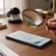 Magnifying glass over smartphone settings screen used to detect spy apps on phone
