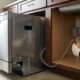 Electrician checking dishwasher amp requirements while wiring a junction box under a kitchen sink